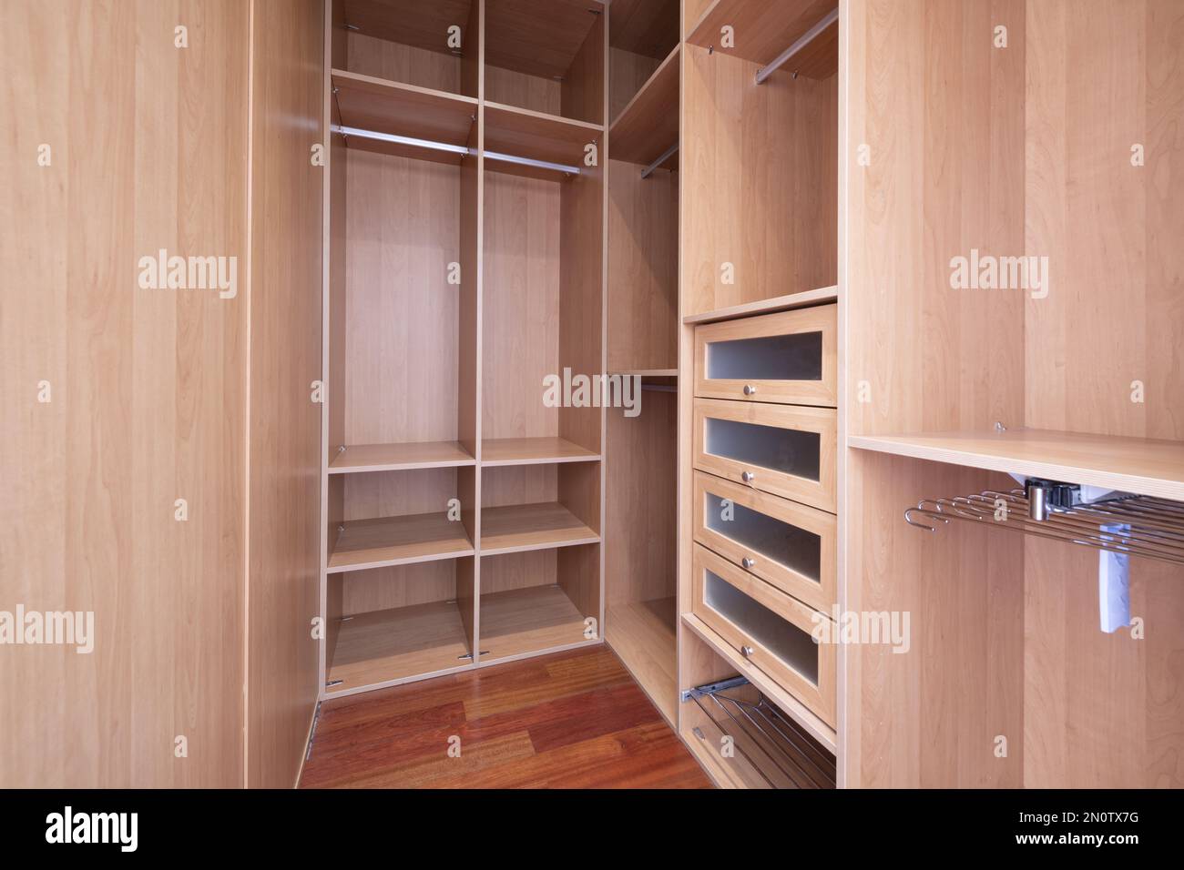 Interior of an empty walkin closet with drawers, hangers, bars for
