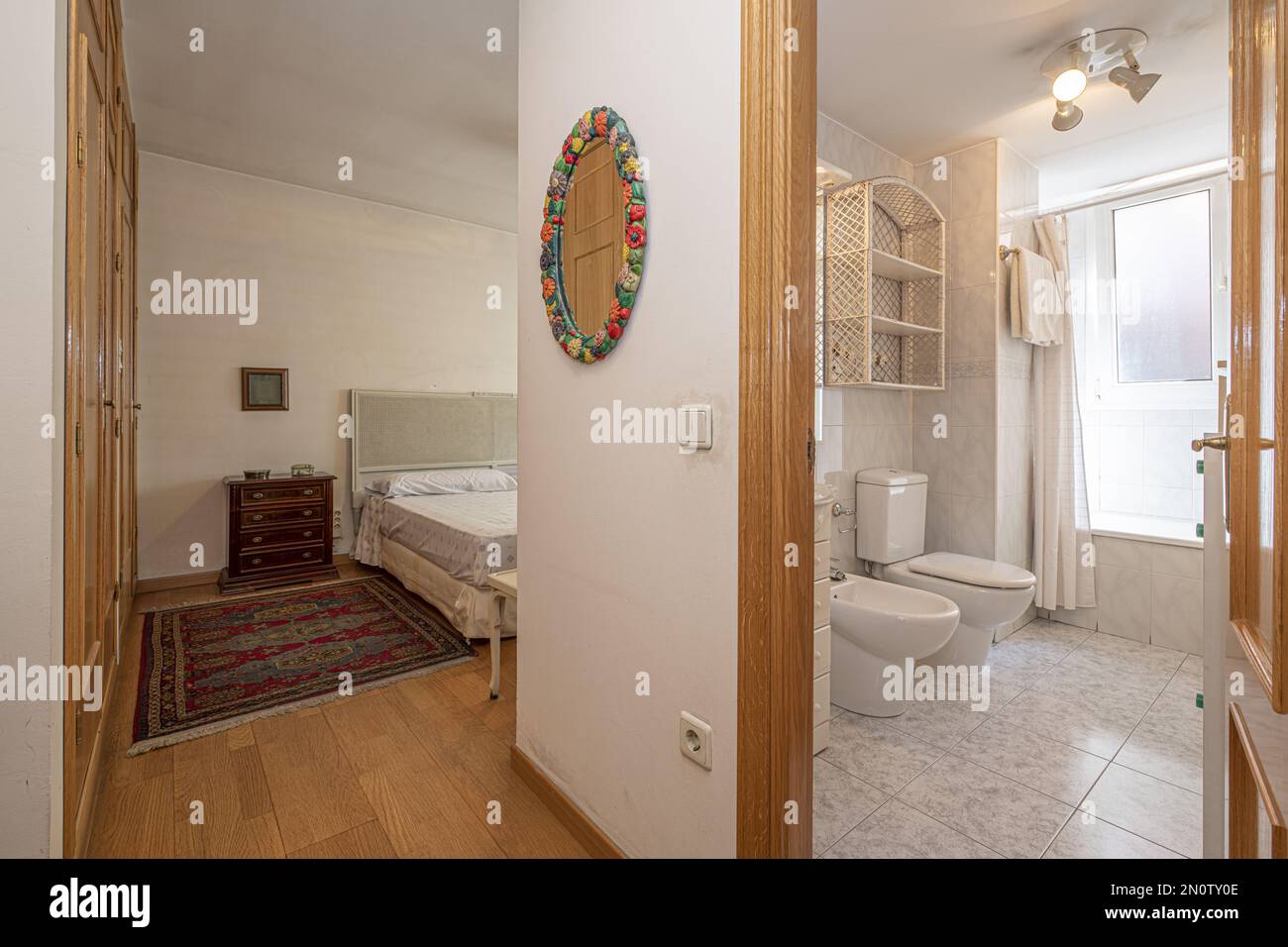 Double bedroom with built-in wardrobe and an en-suite bathroom with a bathtub with curtains Stock Photo