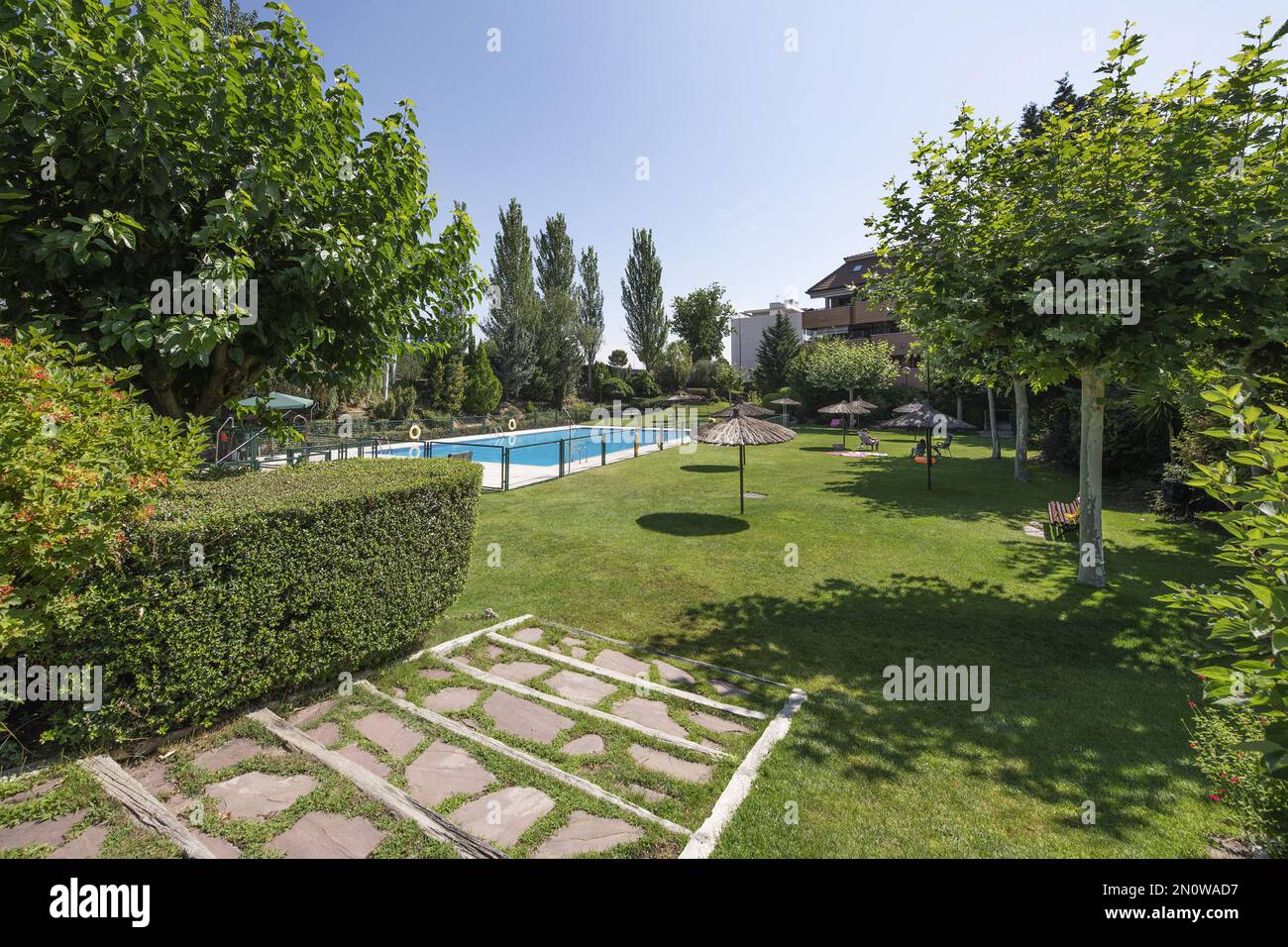 Shared Communal Pool A beautiful communal area with a swimming pool, straw beach umbrellas ...