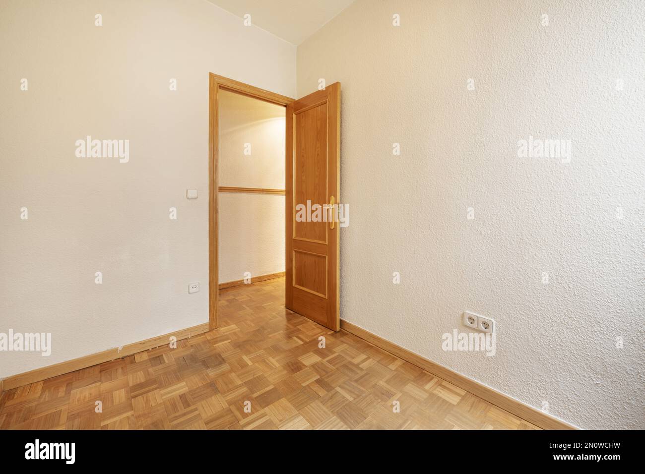 Empty room with gotelet white painted walls, oak wooden doors and matching skirting boards and oak parquet slatted floors laid in a checkerboard patte Stock Photo