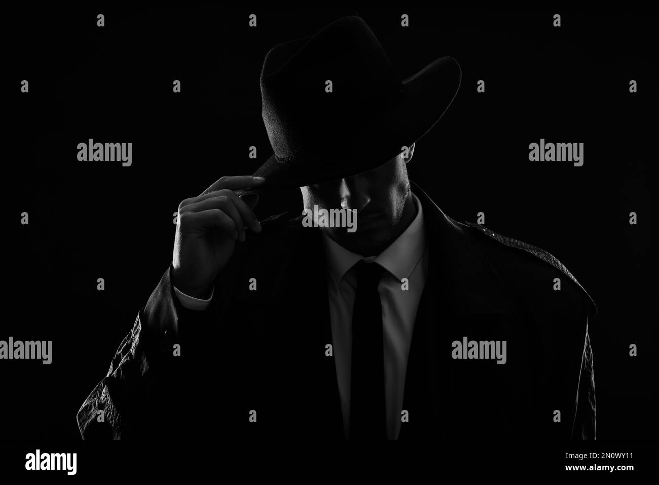 Old fashioned detective in hat on dark background, black and white ...