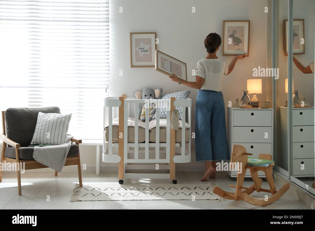 Decorator hanging pictures on wall in baby room. Interior design Stock ...