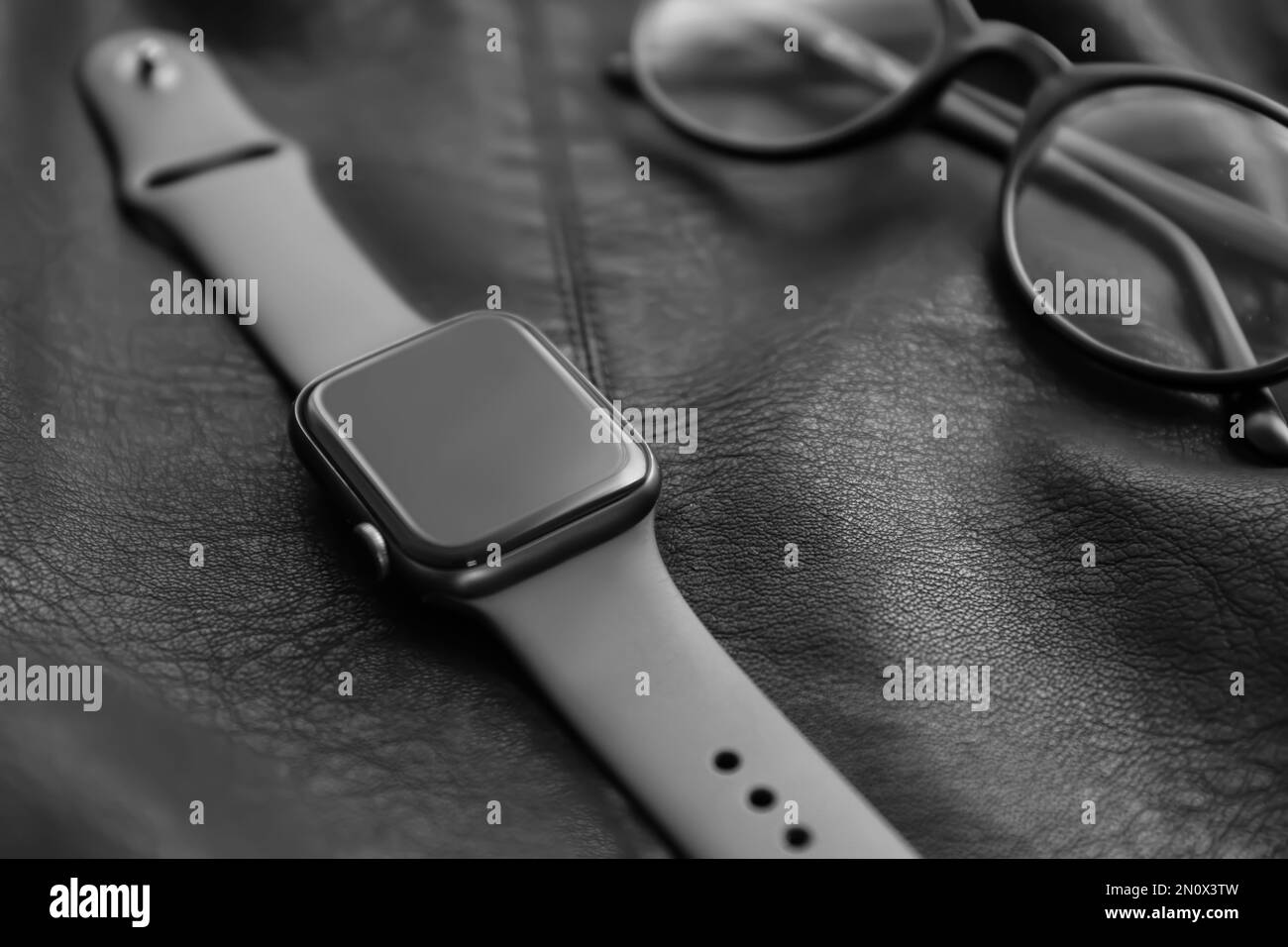 Stylish smart watch and glasses on black leather fabric, closeup Stock Photo
