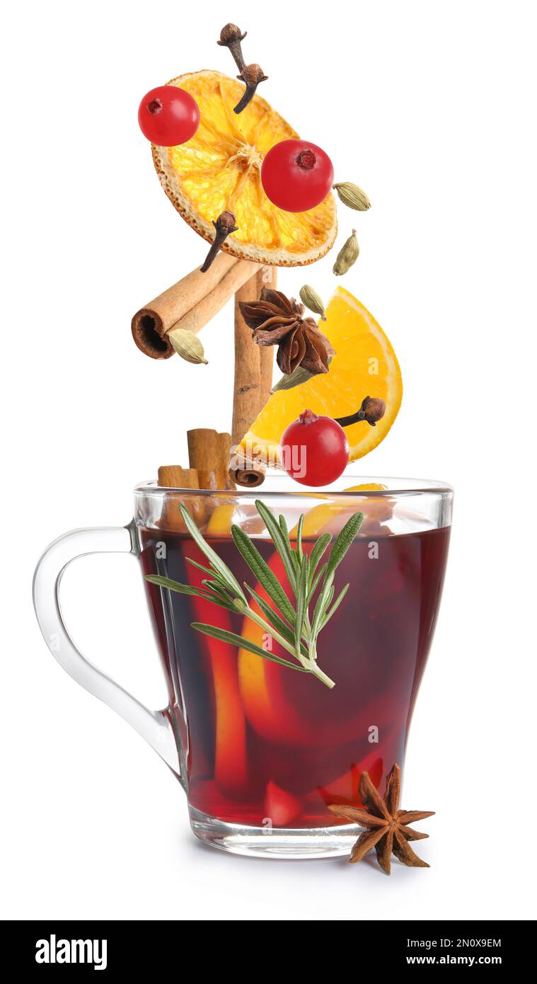 Cut orange, cranberries and different spices falling into glass cup of mulled wine on white background Stock Photo