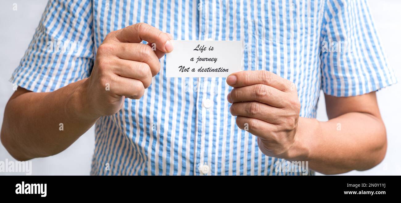 Man holding a white business card with text, Life is a journey not a destination. Stock Photo