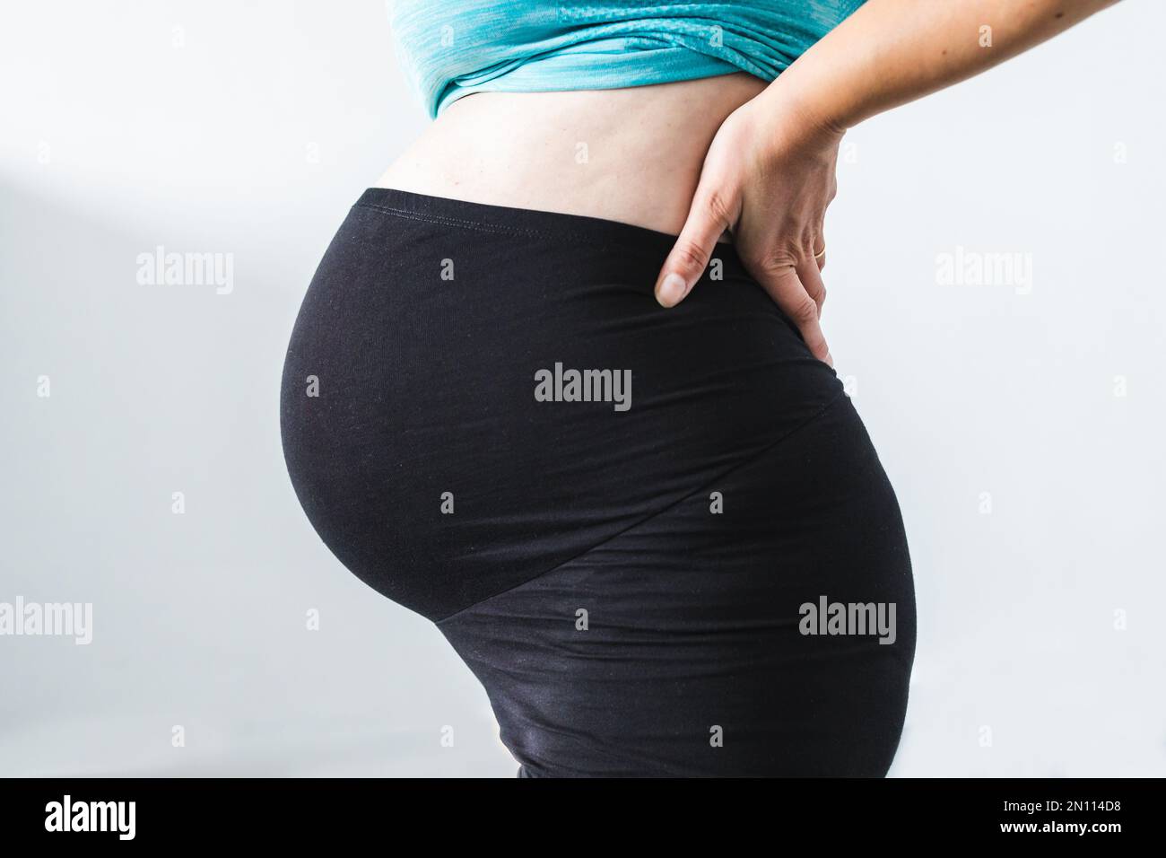 pregnant woman touching her bump in the latest stage of pregnancy, mid