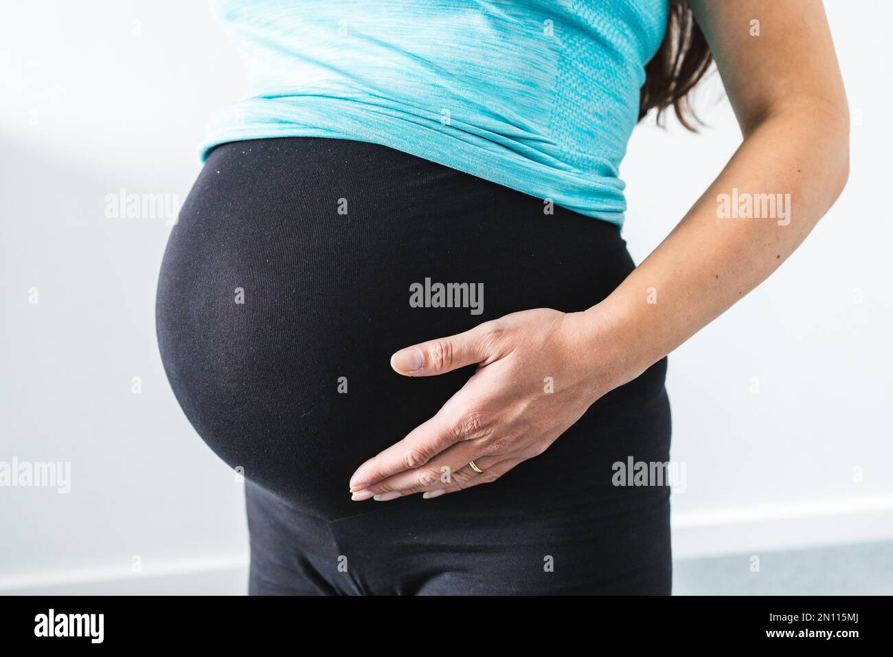 pregnant woman touching her bump in the latest stage of pregnancy, mid