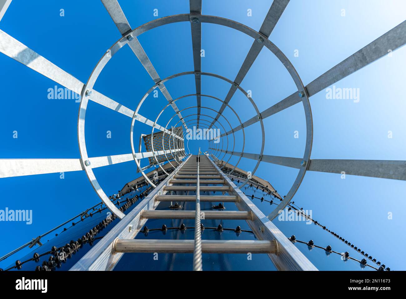 Vertical metal ladder with cage along the side of a water tank Stock