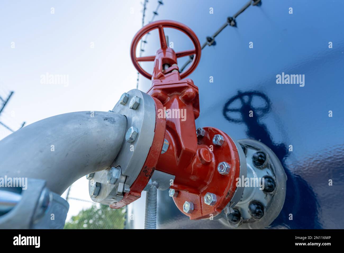 Red water valve on the side of a blue water tank. Stock Photo