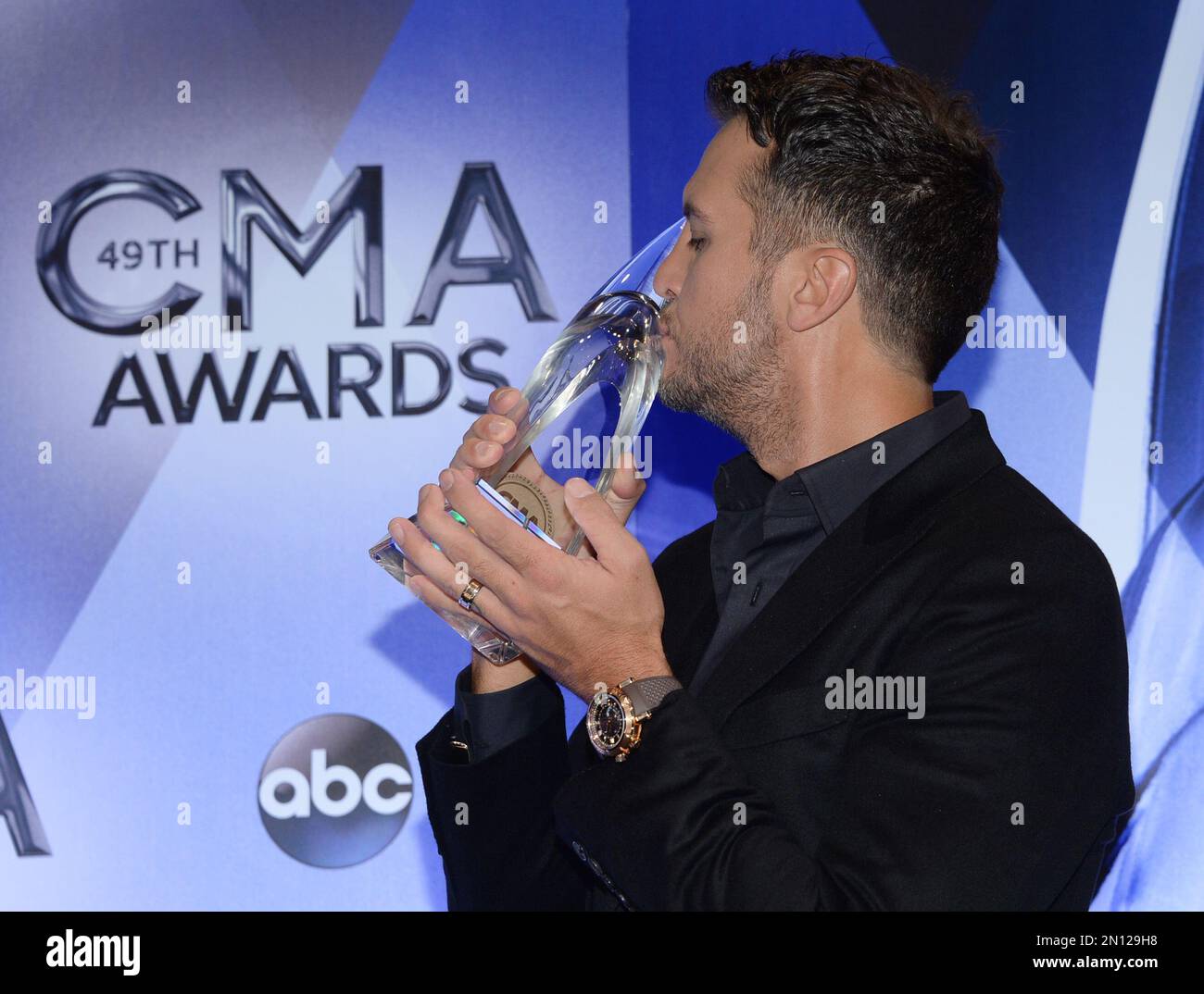 Luke Bryan, winner of the award for entertainer of the year, kisses his