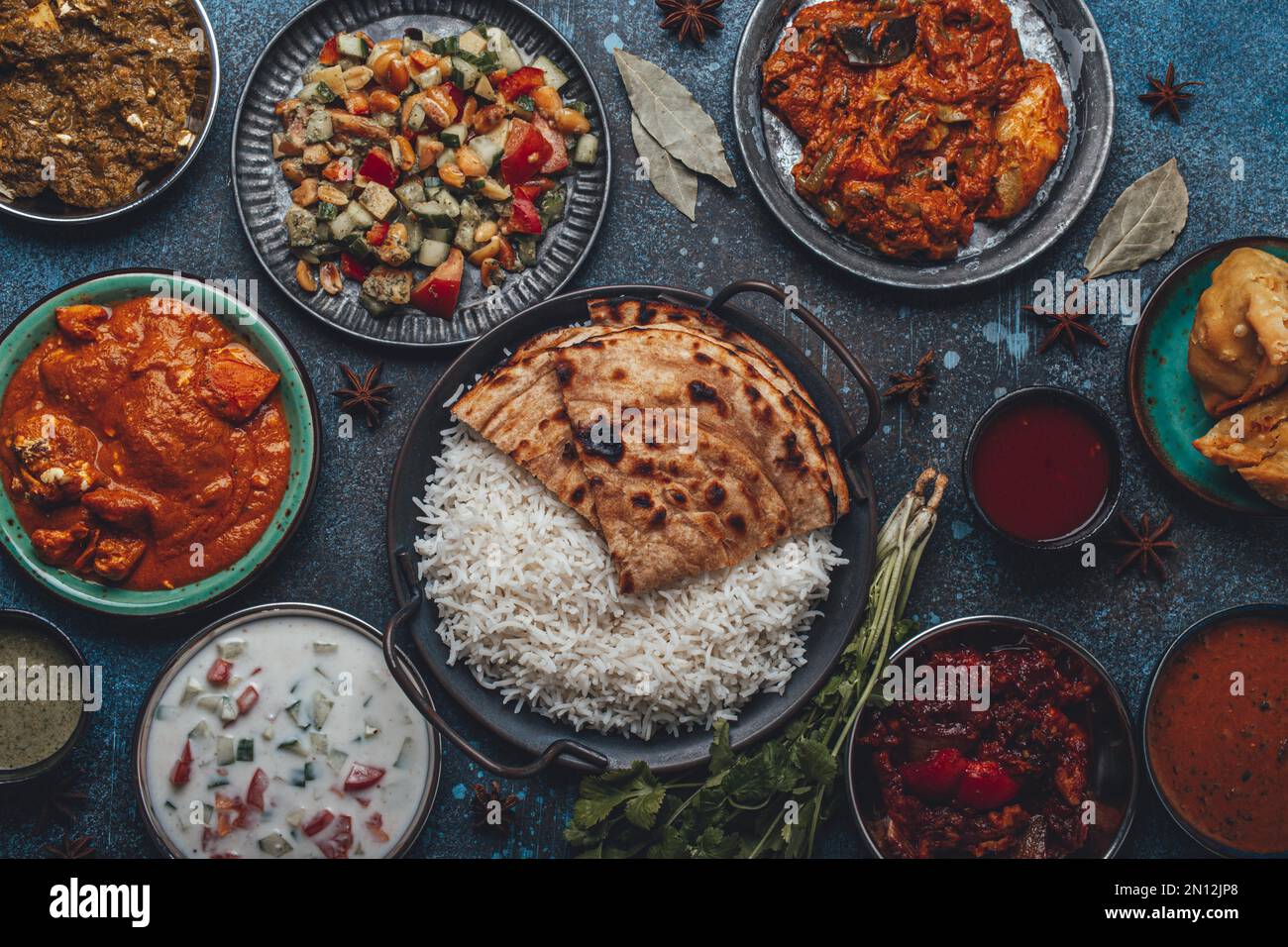 Assorted Indian ethnic food buffet on rustic concrete table from above