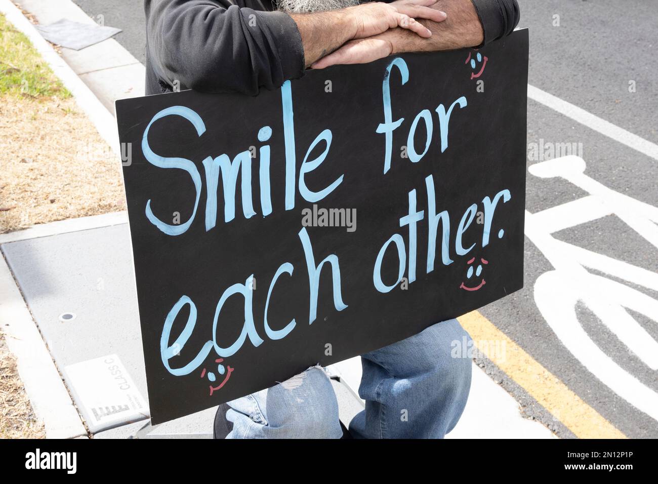 smile for each other hand written sign on chalk board Stock Photo