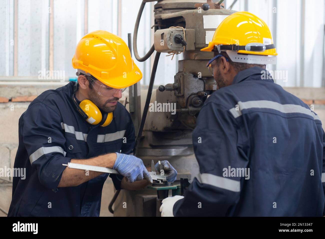 Engineer man training with foreman for apprentice using lathe, apprenticeship teaching with worker, technician and learning, inspector and labor, inte Stock Photo