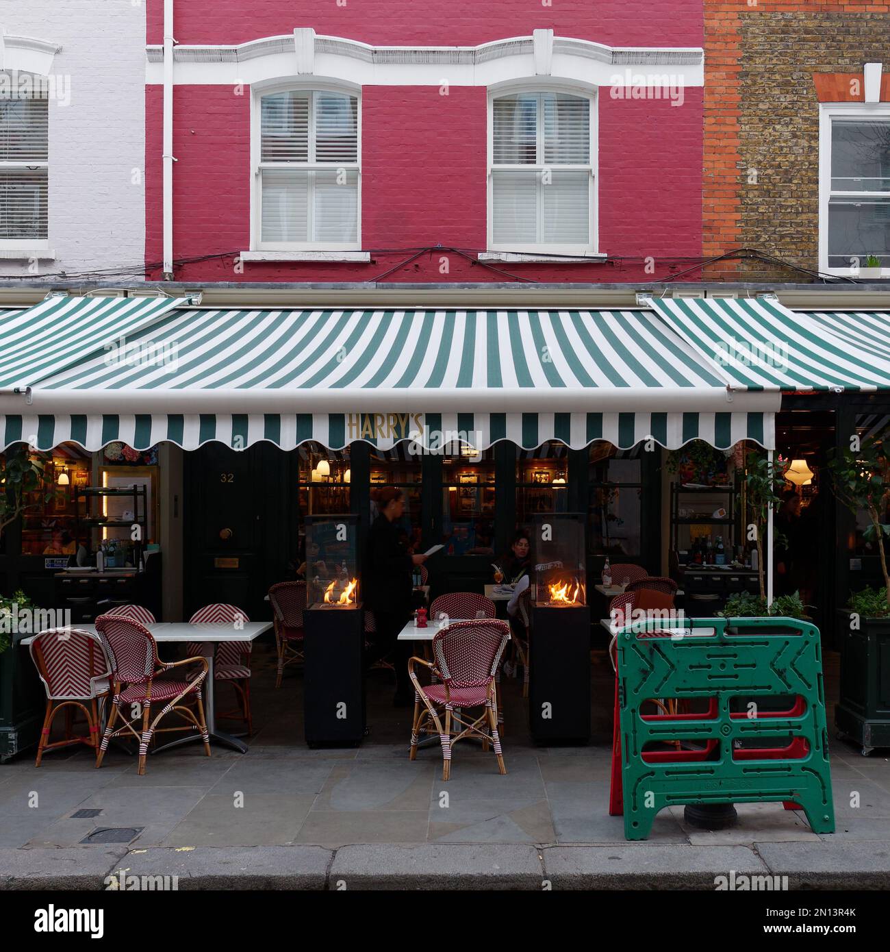 Cafe / restaurant with green and white awning and a red facade. London England. External heaters used on a winters day Stock Photo