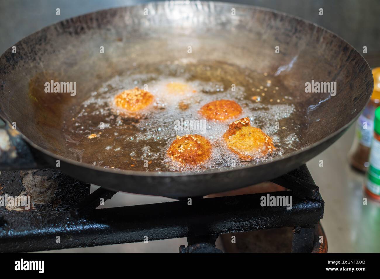Deep frying falafel balls in a wok, hot cooking oils bubbling, and