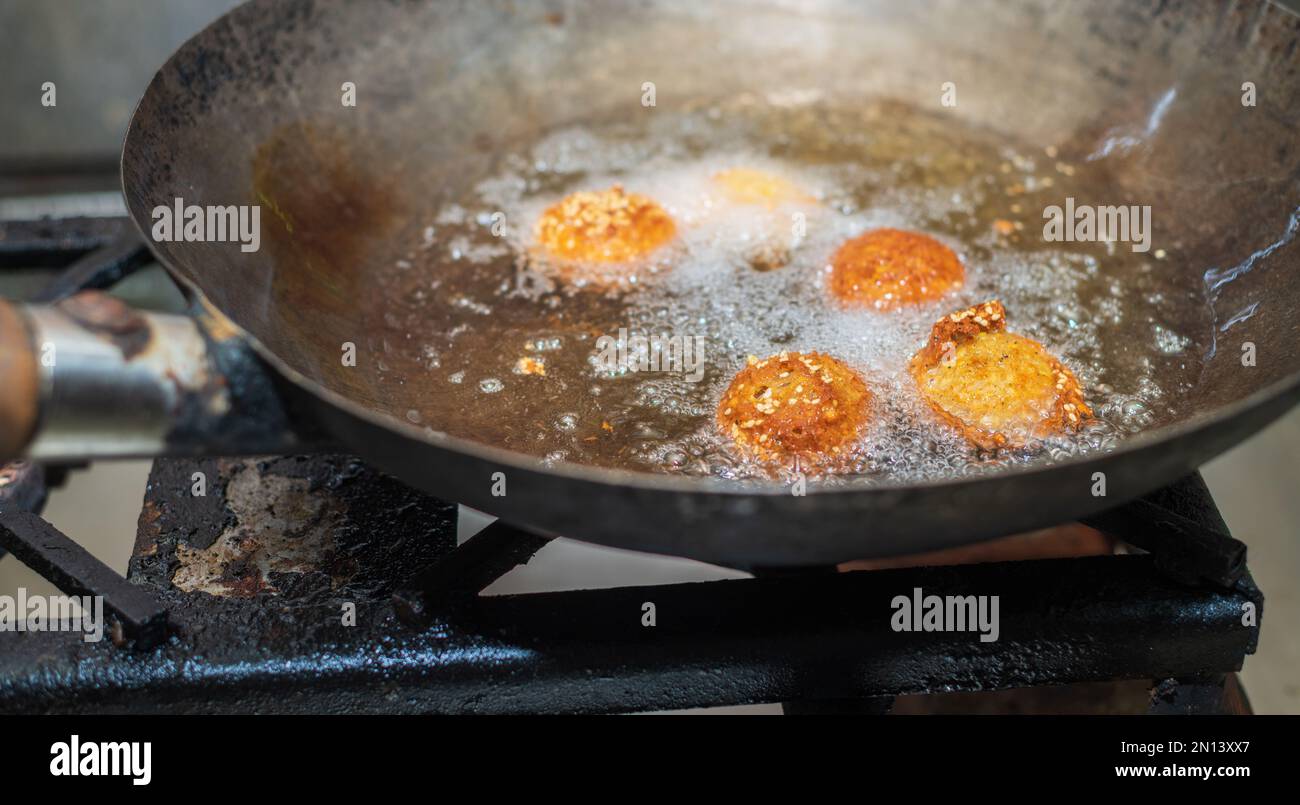 Deep frying falafel balls in wok, hot cooking oils bubbling and falafel