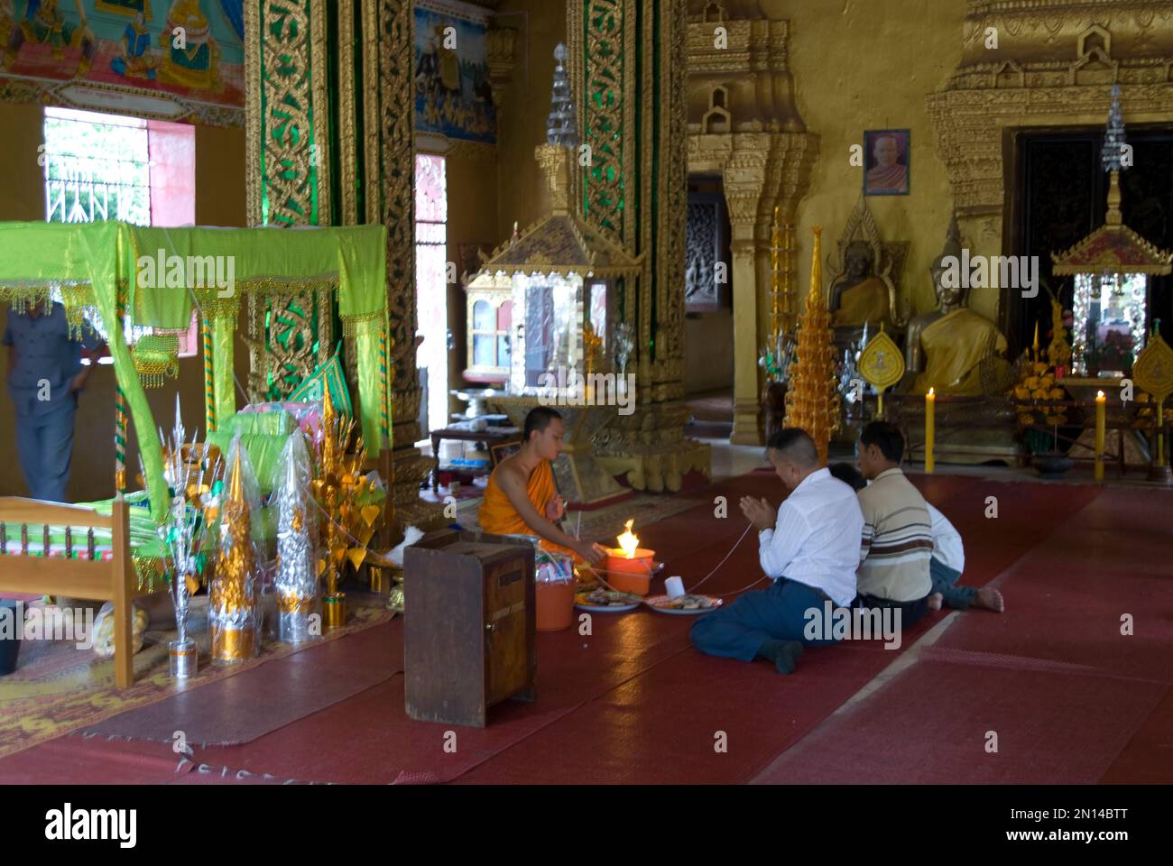Monk performing holy thread ceremony on locals, Wat Si Muang, Vientiane ...