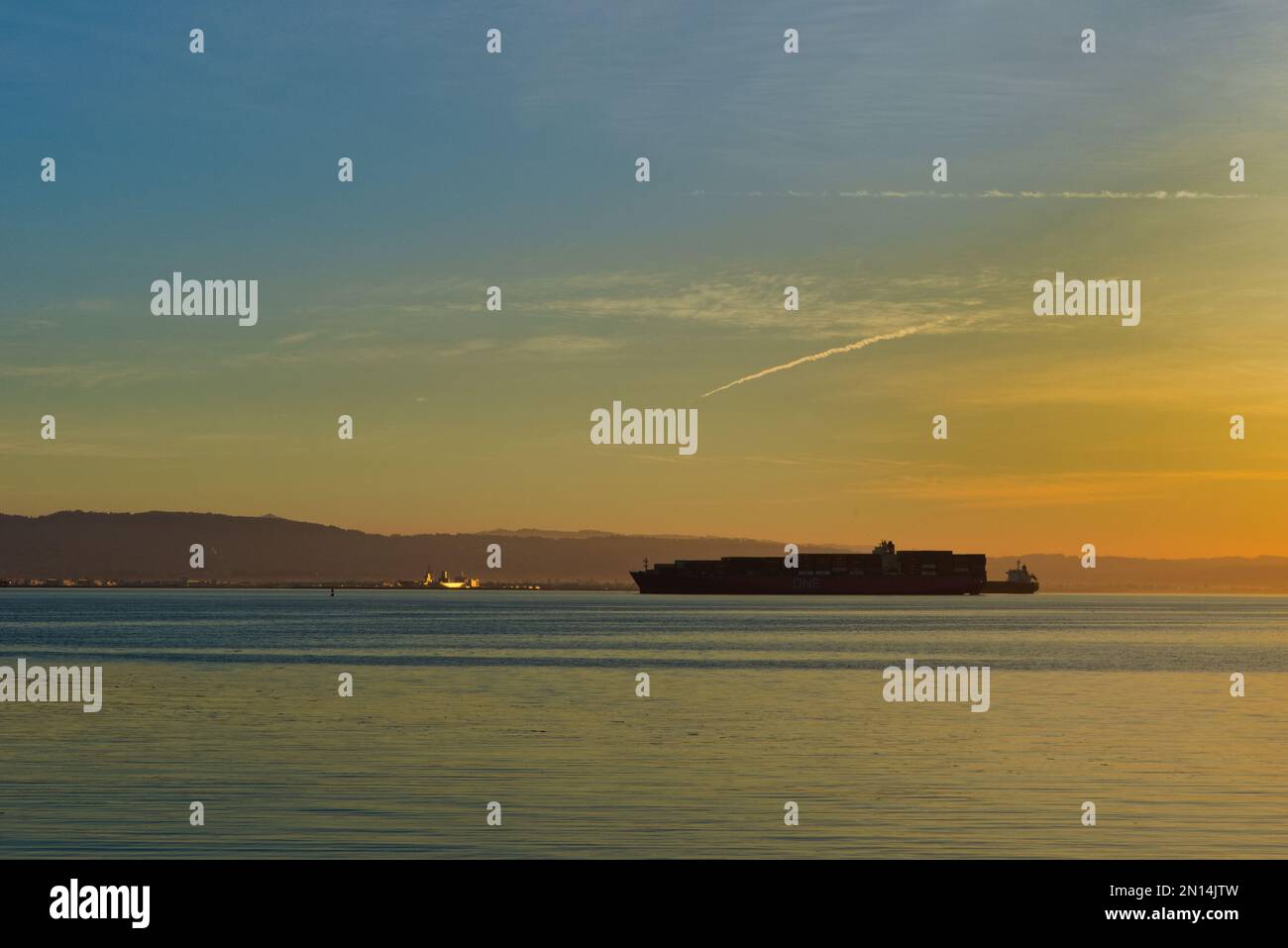 Large cargo ship sitting in San Francisco Bay during sunrise at Warm Water Cove Park. San Francisco, California, USA Stock Photo