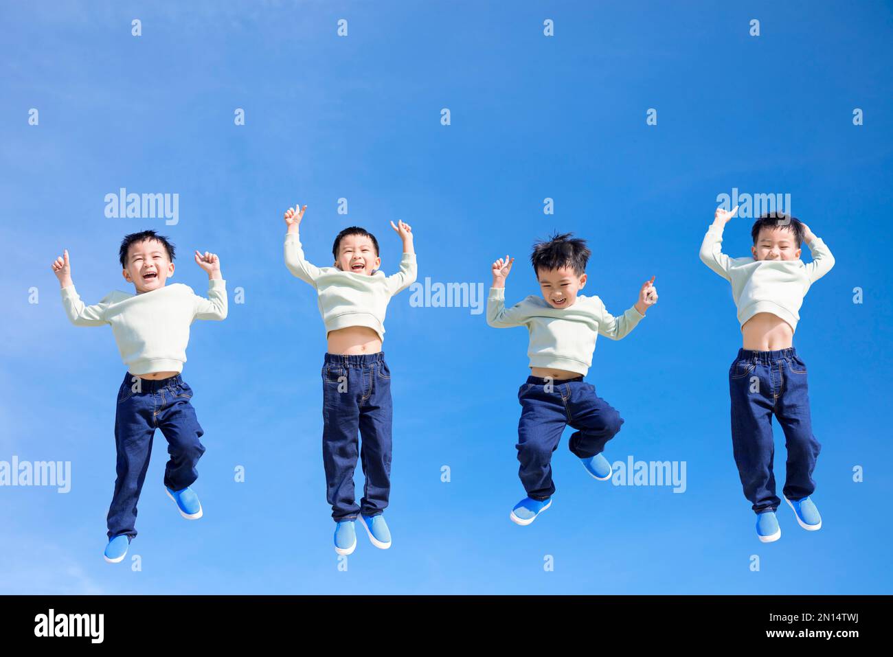 Happy kid jumping and gesturing against blue sky Stock Photo