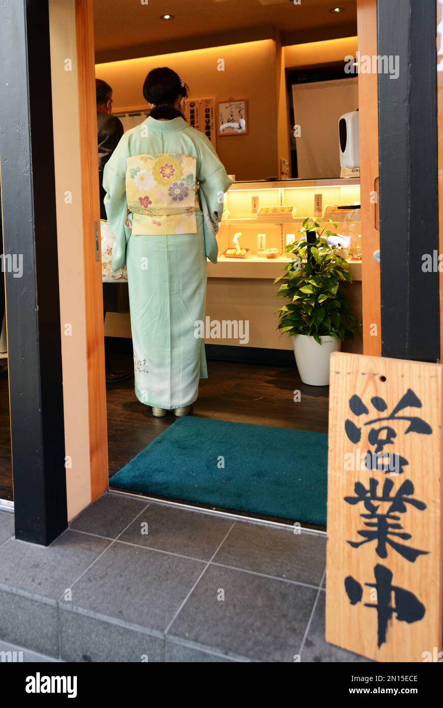 A Japanese woman dressed in traditional kimono buying traditional food
