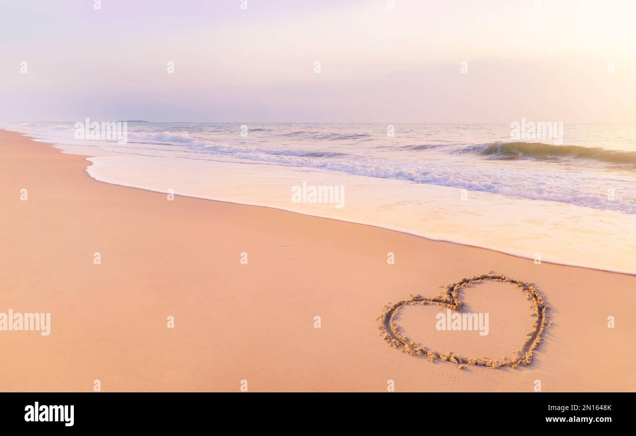 Draw a heart shape on the sandy beach in the morning. to welcome Valentine's Day festival. Stock Photo