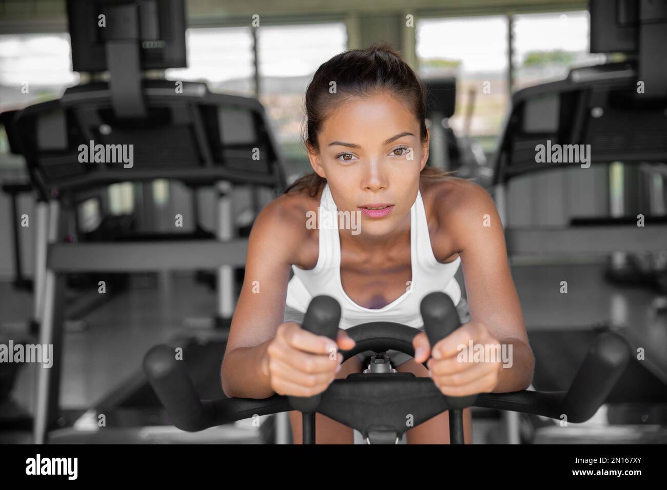 Gym fitness class fit woman riding spin bike doing hiit exercise cycling doing cardio workout