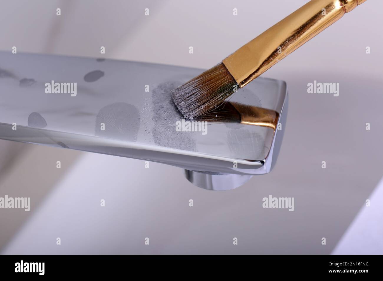 Using brush and powder to reveal fingerprints on faucet indoors, closeup Stock Photo