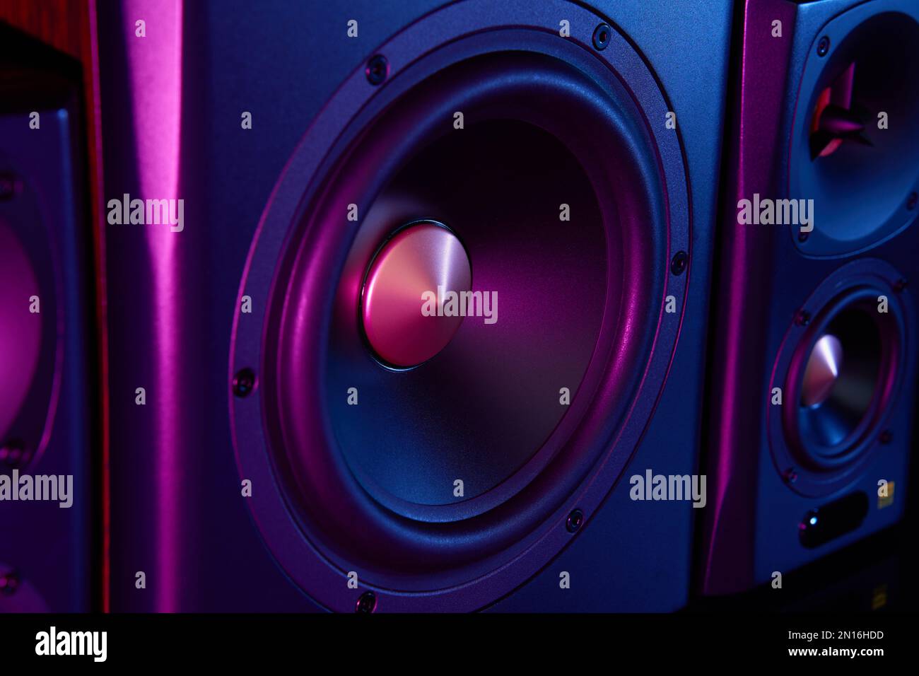 Two sound speakers and subwoofer on dark background with neon lights