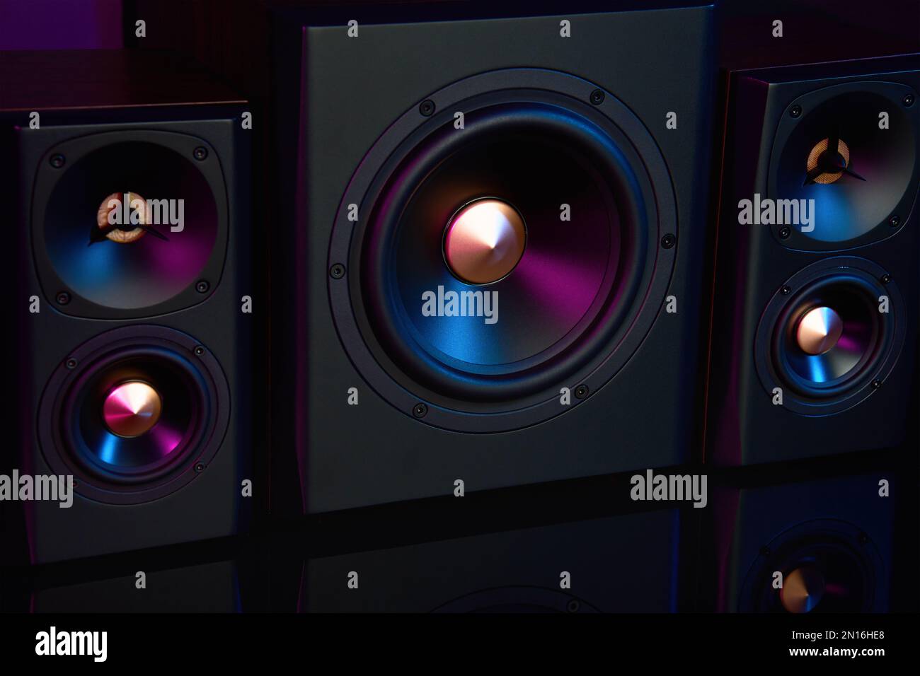 Two sound speakers and subwoofer on dark background with neon lights ...