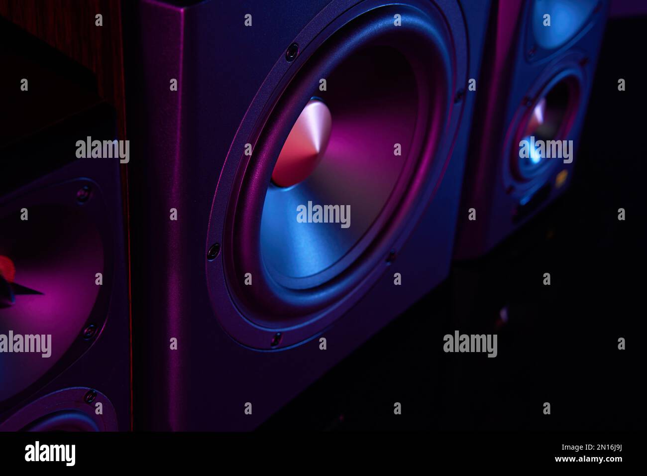 Two sound speakers and subwoofer on dark background with neon lights ...