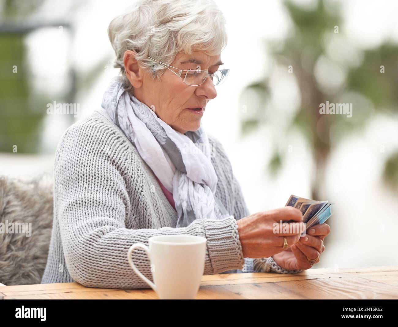 Dont hate the player, hate the game. a senior woman holding a stack of cards in her hand. Stock Photo