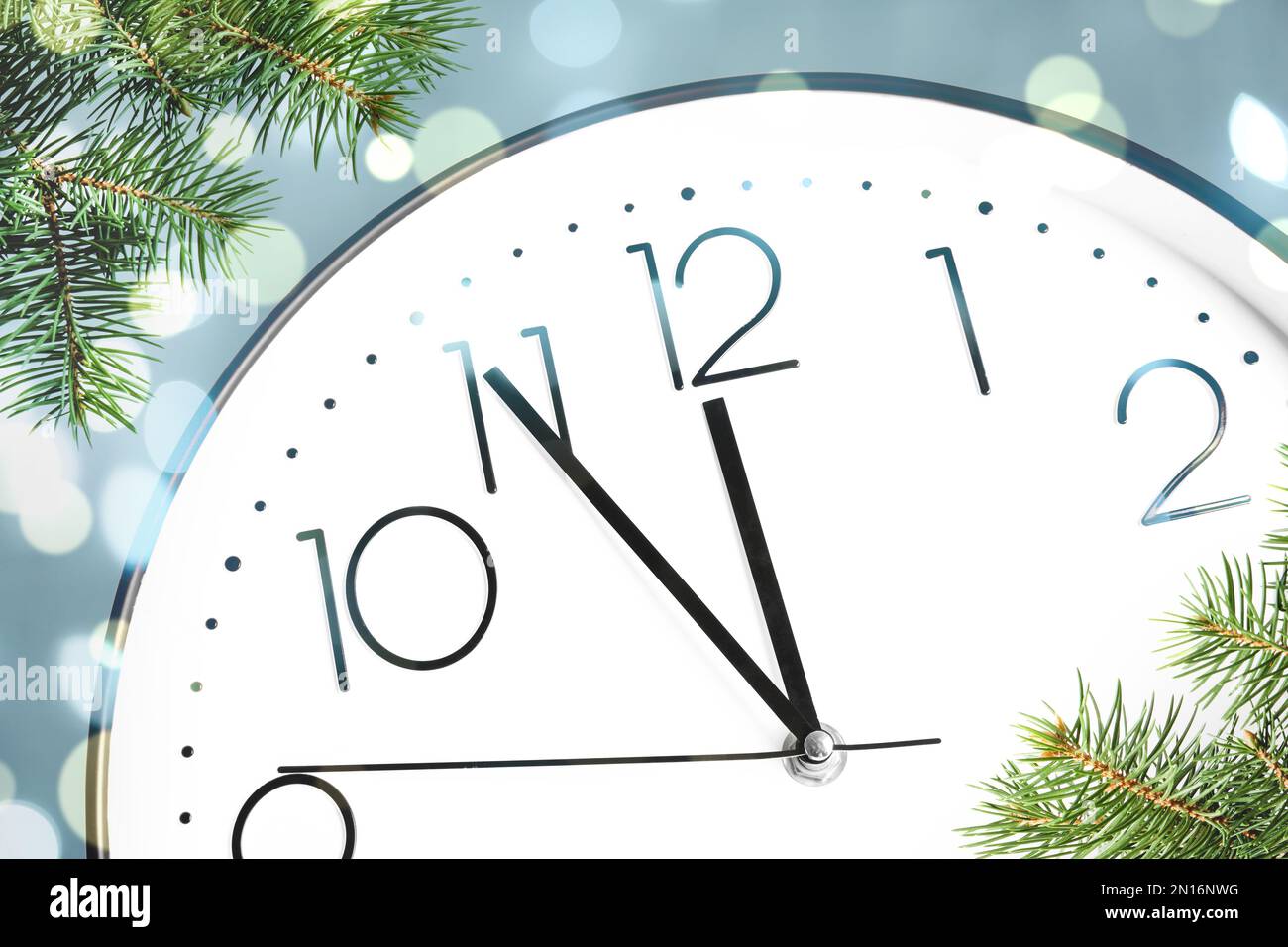 Clock showing five minutes till midnight with fir tree branches