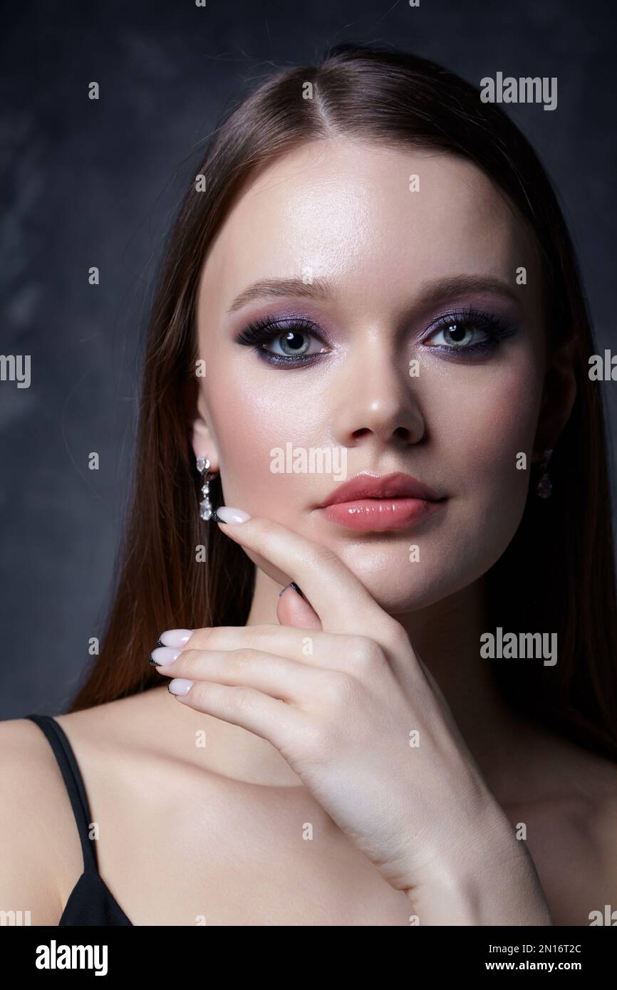 Portrait of female face. Hand with black french manicure nailsnear face