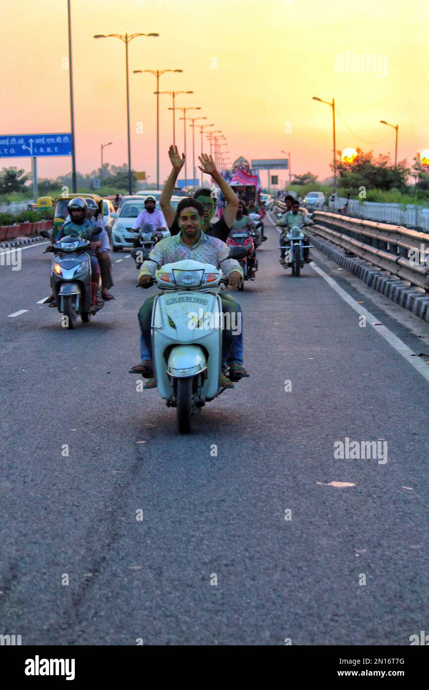 A vertical shot of Indian people going to worship God Ganesh  on motorcycles at sunset Stock Photo