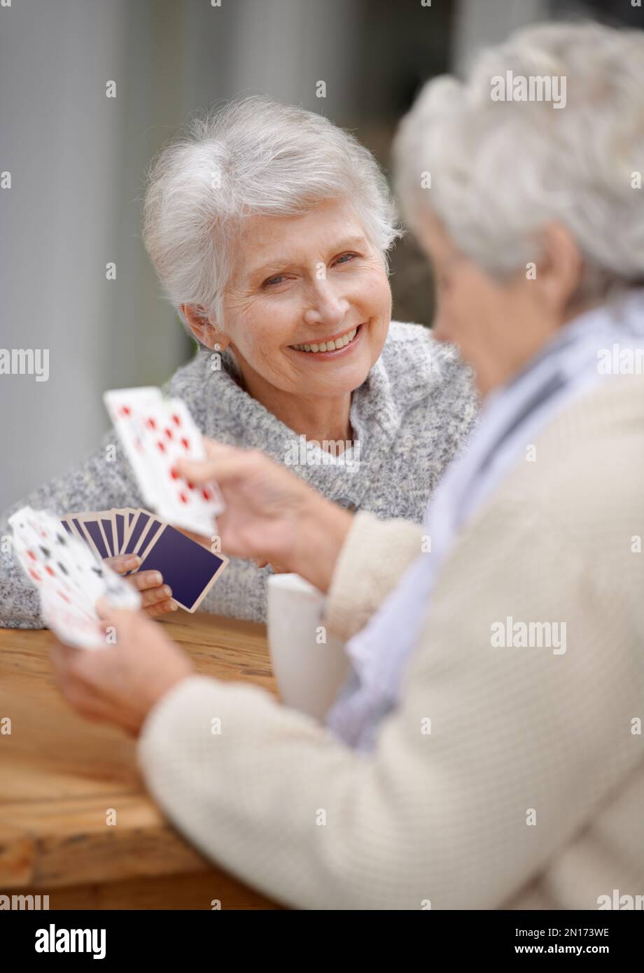 Helping the time pass with card games. Two senior women playing cards