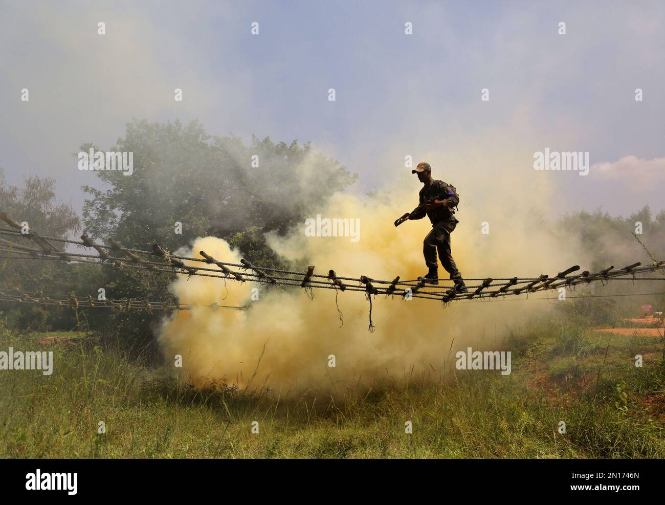 An Indian army soldier crosses a rope bridge amid smoke from canisters ...