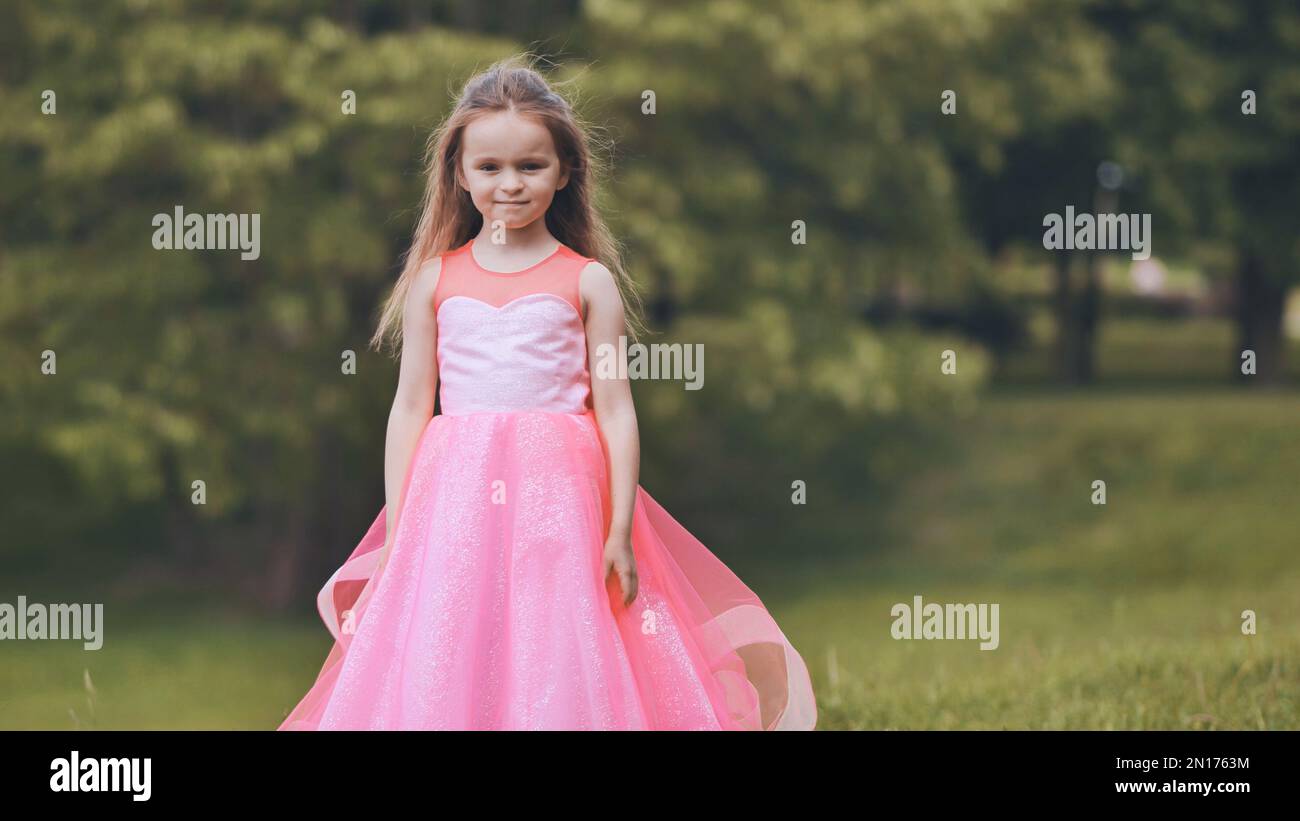 Portrait of a little girl in a pink dress in the park Stock Photo