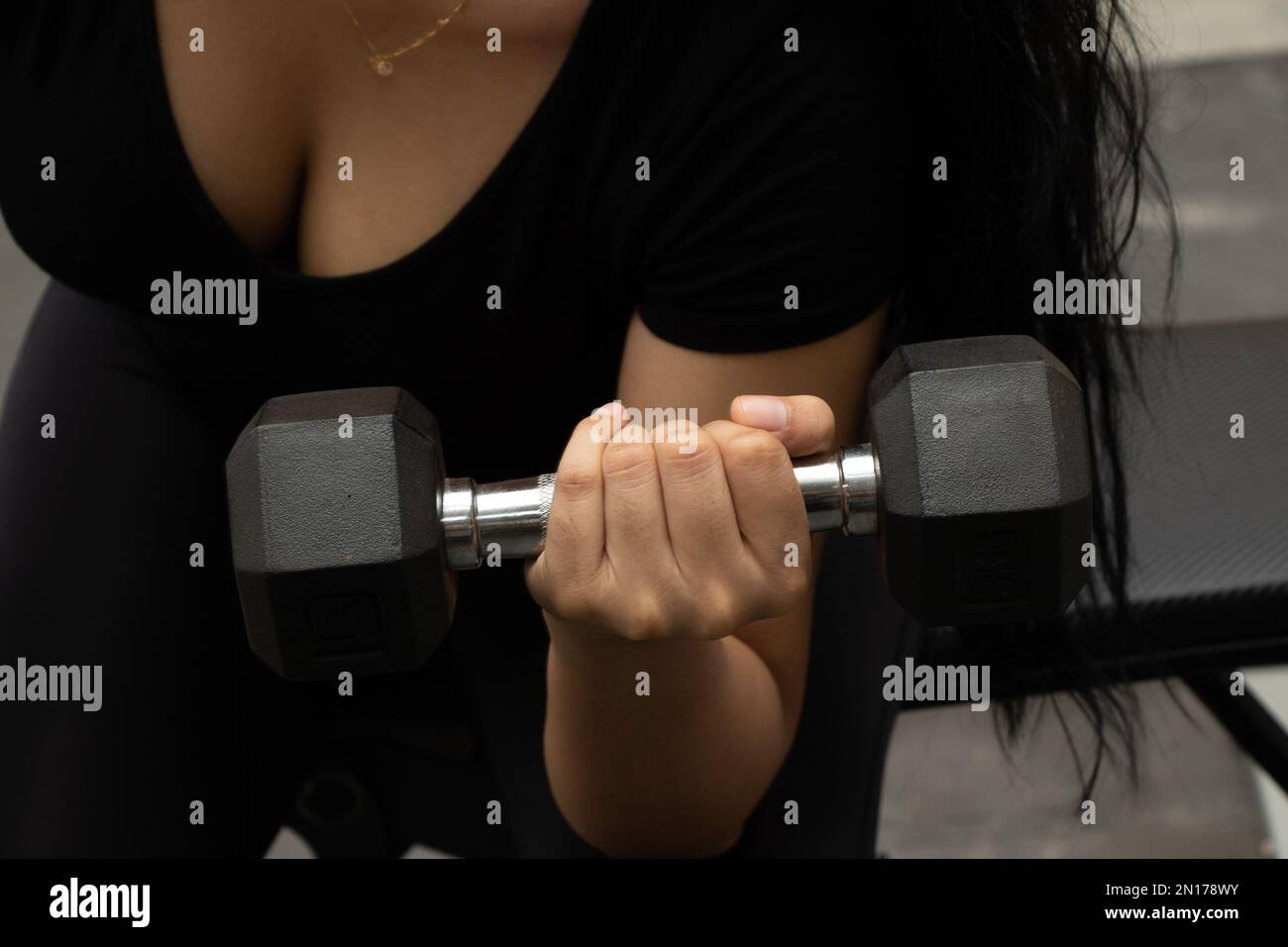 Woman exercising with a dumb bell in a gym Stock Photo