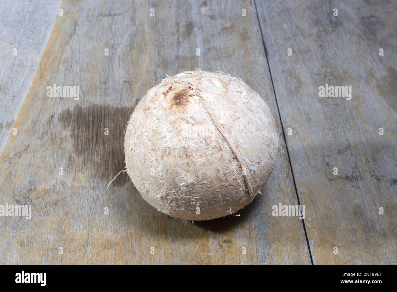 Fresh raw single coconut closeup isolated on wooden background Stock Photo
