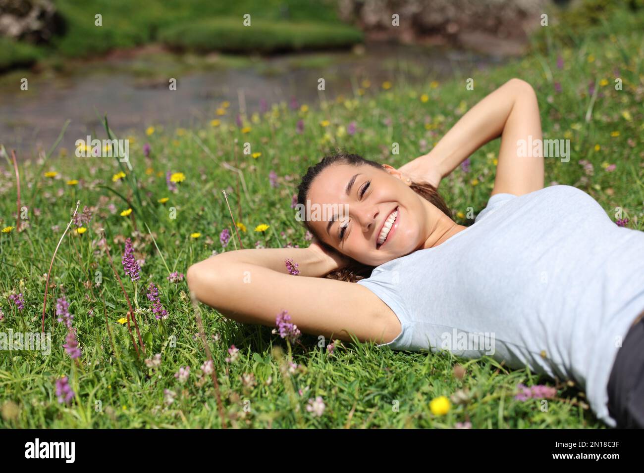 Relaxed woman lying on the grass in a riverside looking at you Stock Photo