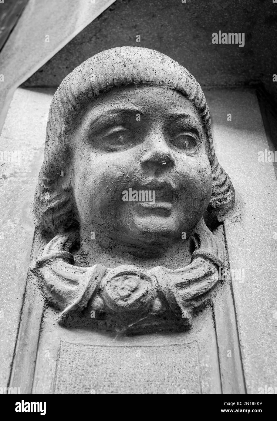 black and white photograph of a statue of a child's head on the entrance wall of an old building in Vienna, Austria Stock Photo