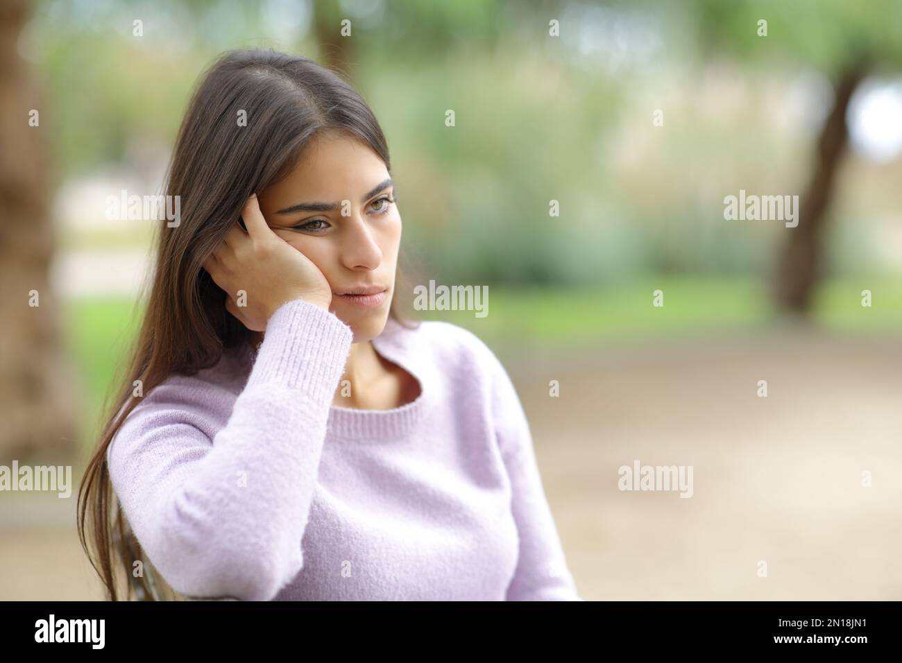 Bored woman sitting in a park alone Stock Photo