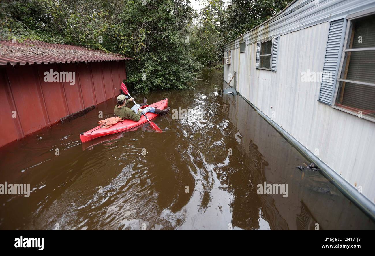 Kip Jones uses a kayak to survey flooding on Roundtree Road along the