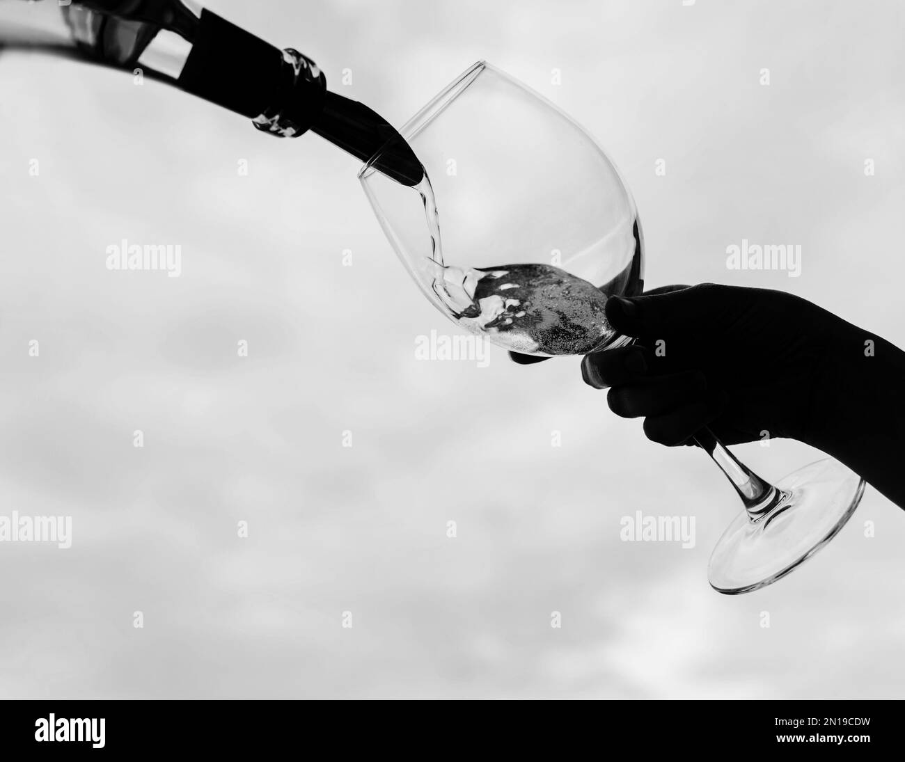 Girl pouring champagne into glass over sky background Stock Photo Alamy