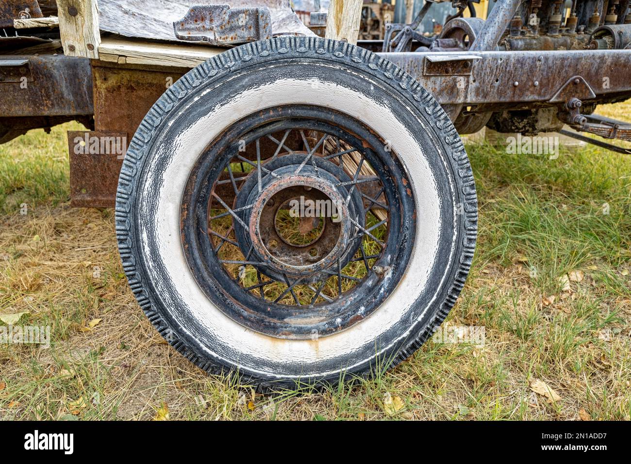 An antique whitewall tire with spokes resting in grass Stock Photo