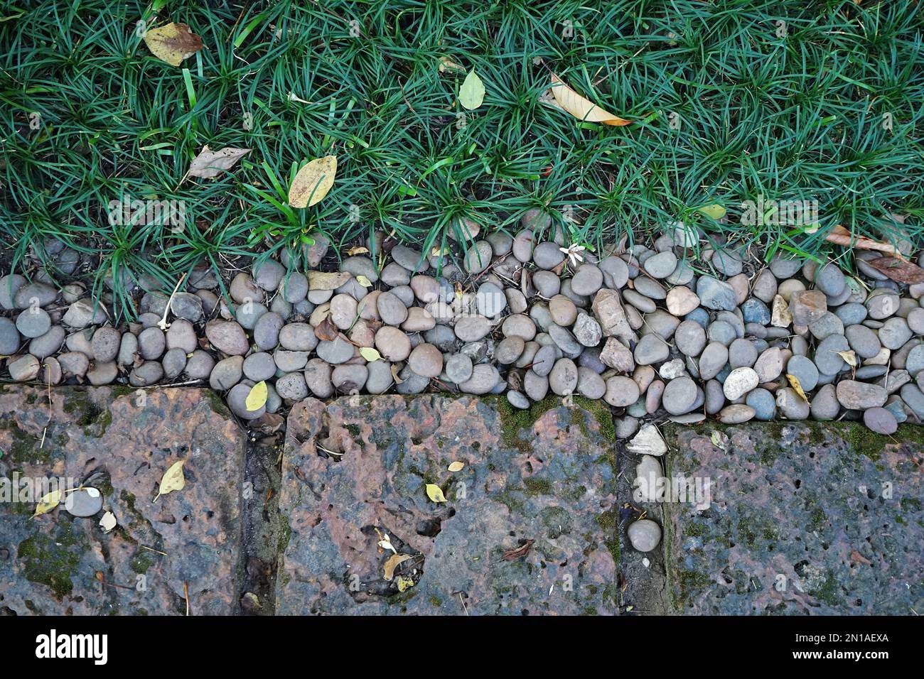 Arrangement of green grass with natural paving stone and clay tiles Stock Photo