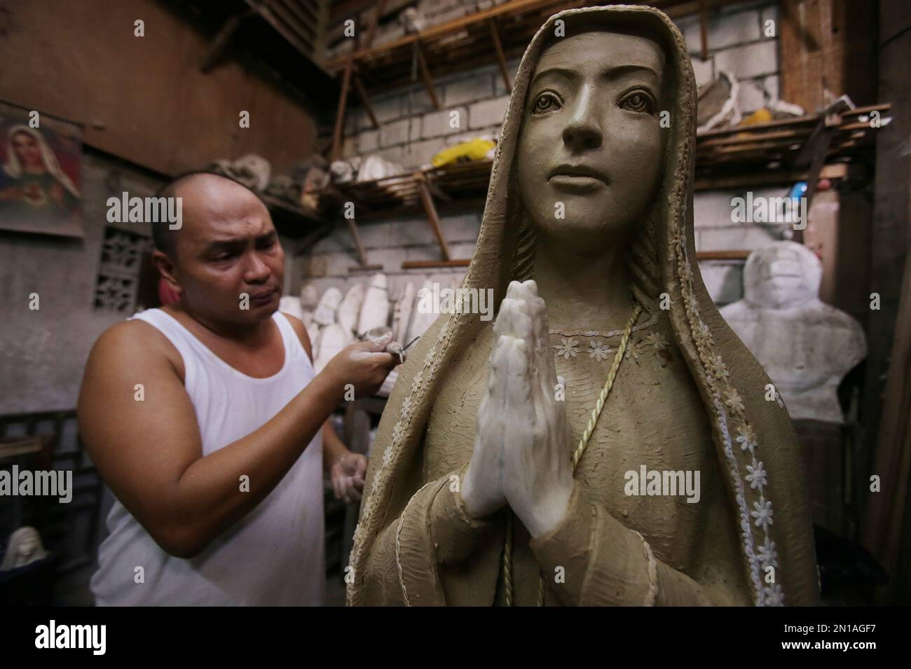 Filipino sculptor Frederic Caedo shapes pottery clay to make an image