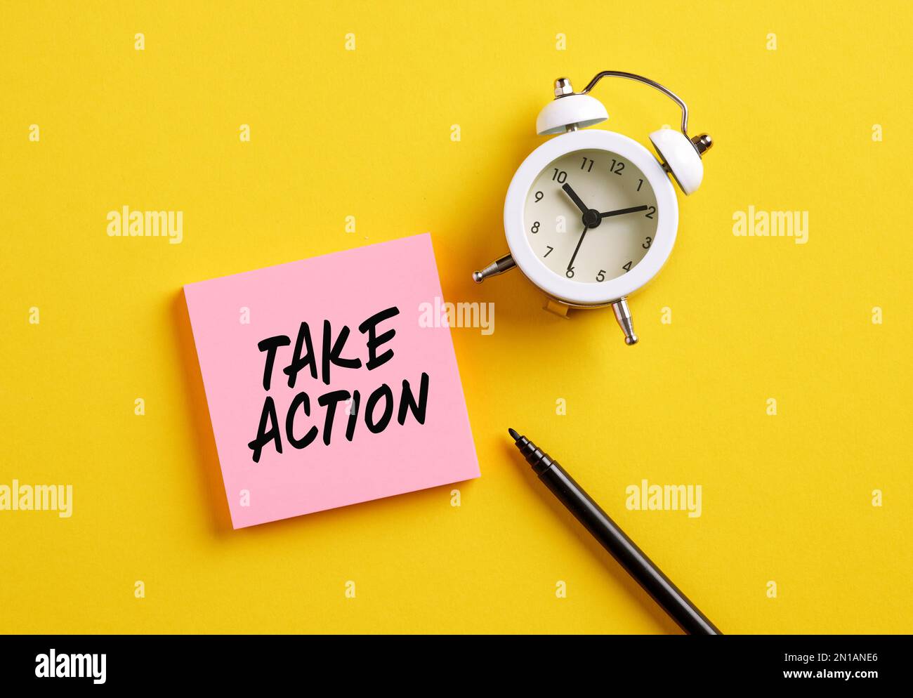 Take action message on pink note paper with alarm clock and pen. Motivational message for taking action in business or life concept. Stock Photo