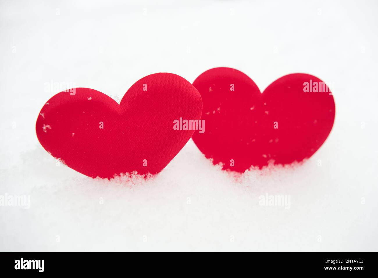 Two red heart shape on natural pure white soft snow surface side by ...