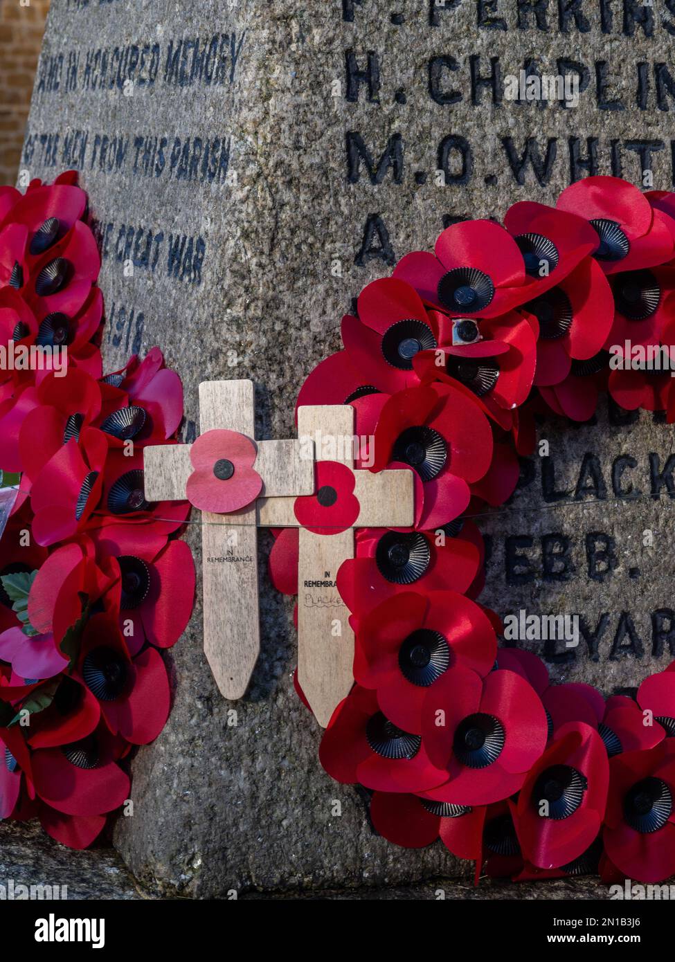 Close up of poppy wreaths and poppy crosses on a WW1 memorial, in the churchyard of St George the Martyr, Wootton, Northampton, UK Stock Photo